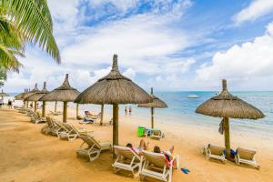 a group of beach chairs and umbrellas on a beach at Casuarina Resort and Spa in Trou aux Biches