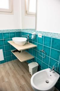 uma casa de banho em azulejos azuis com um lavatório e um WC em B&B Il Viaggiatore em Tortolì