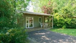 una pequeña casa verde con porche y mesa en Terres de France - Moncontour Active Park, en Moncontour-de-Poitou