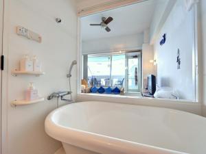 uma banheira branca na casa de banho com uma janela em Sound Swell Resort em Minamiboso