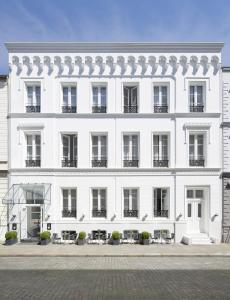Un edificio blanco con mesas y sillas delante. en Aussen Alster Hotel, en Hamburgo