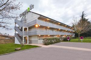 Un grand bâtiment blanc avec des escaliers sur son côté dans l'établissement Campanile Chanas, à Chanas