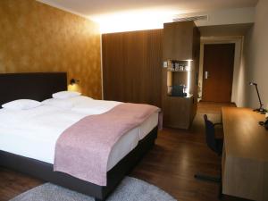 Habitación de hotel con cama grande y escritorio. en Best Western Premier Hotel Rebstock, en Würzburg