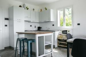 a kitchen with white cabinets and a kitchen island with stools at Agriturismo Oltrealmare in Civezza