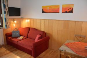 a living room with a red couch and a table at Pension Kreischberg Mayer in Sankt Lorenzen ob Murau