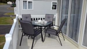 a black table and four chairs on a porch at Porth Retreat at Newquay Bay Resort in Newquay