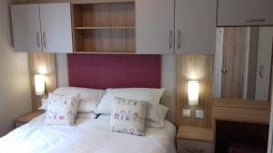 a bedroom with a white bed with white cabinets and pillows at Porth Retreat at Newquay Bay Resort in Newquay