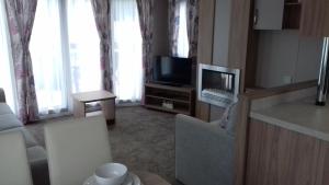 a living room with a couch and a television at Porth Retreat at Newquay Bay Resort in Newquay