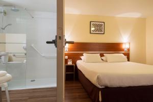 a hotel room with a bed and a shower at Comfort Hotel Aeroport Lyon St Exupery in Saint-Exupéry