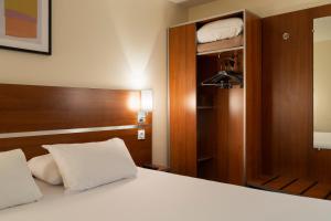 a bedroom with a bed with a wooden headboard at Comfort Hotel Aeroport Lyon St Exupery in Saint-Exupéry