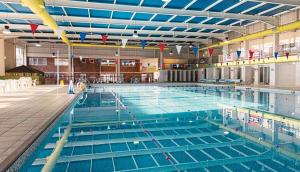a large swimming pool with blue water in a building at Porth Retreat at Newquay Bay Resort in Newquay +10 photos