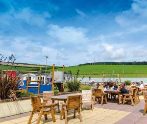 a group of people sitting at a table near a river at Porth Retreat at Newquay Bay Resort in Newquay