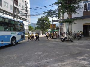 um grupo de pessoas atravessando uma rua ao lado de um ônibus em Khách sạn Sea Hải Yến em Da Nang