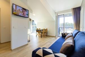a living room with a couch and a tv on a wall at Sunny Pines Apartment in Palanga
