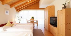 two beds in a room with a table and a television at Residence Walder in Falzes
