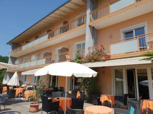 a hotel with tables and chairs and an umbrella at Pension Krakolinig in Pörtschach am Wörthersee