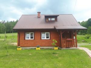 een klein houten huis met een dak bij Domek Gajowego in Ropienka