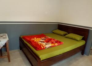 a bed with a green and red blanket on it at Homestay Anggun Bromo in Bromo