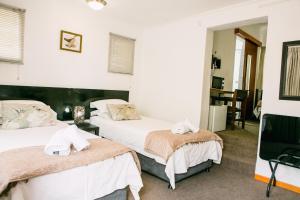 two beds in a room with white walls at Pennylane Guest House in Ermelo
