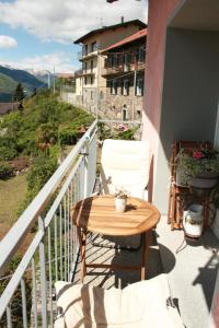 una mesa de madera y una silla en el balcón en Vista Lago en Maccagno Superiore