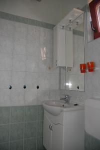 a white bathroom with a sink and a mirror at Apartments Judit in Tar