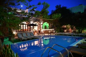 a swimming pool with chairs and a house at Philoxenia Hotel & Studios in Perissa