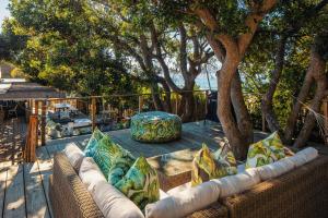 un patio con sofá, mesa y árboles en The Bungalow by Raw Africa Collection, en Plettenberg Bay