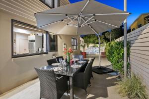 a table with an umbrella on a patio at Waihi Beach Paradise Resort in Waihi Beach
