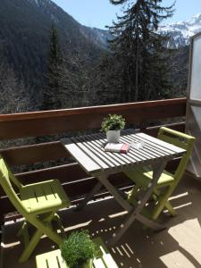 a picnic table and two chairs on a balcony with mountains at Studio à Courchevel Moriond in Saint-Bon-Tarentaise