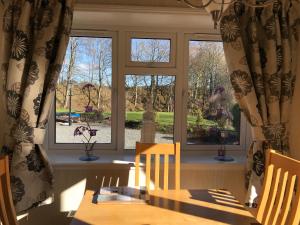 a dining room with a table and two windows at Grand eagles Riverside Extra large lodge in Auchterarder