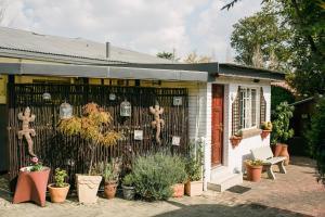 a house with a fence and lots of plants at Pennylane Guest House in Ermelo