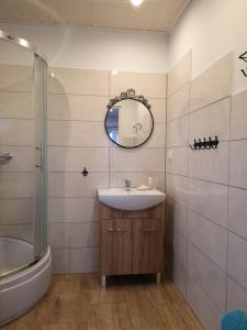 a bathroom with a sink and a tub and a mirror at Domek Gościnny Ustka Przewłoka in Ustka
