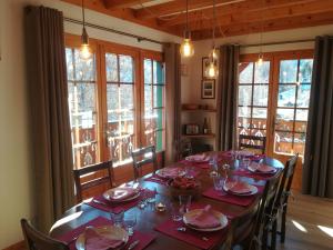 a dining room with a long table with chairs and windows at Chalet Marie Paradis in Saint-Gervais-les-Bains