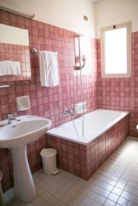 un bagno piastrellato rosa con vasca e lavandino di Hotel San Marco a Lido di Jesolo