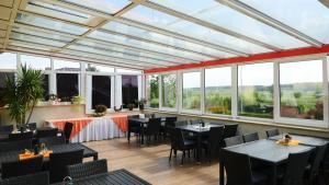 a restaurant with tables and chairs and large windows at Landhaus Mecklenburg in Waren