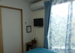 a bedroom with a bed and a window with a television at Kanaloa Funabashi in Funabashi