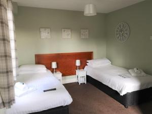 1 dormitorio con 2 camas y reloj en la pared en Chalet Cottages, en Streatley