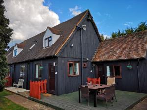 Chalet Cottages في Streatley: منزل أسود مع طاولة وكراسي