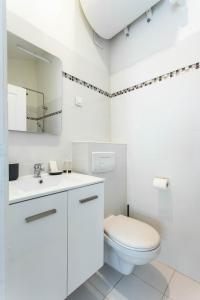 La salle de bains blanche est pourvue de toilettes et d'un lavabo. dans l'établissement CMG Porte d'Orléans - Montrouge, à Montrouge