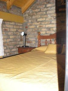 a bedroom with a bed and a brick wall at Cabañas Tierra del Sol Aldea de Montaña in Los Árboles