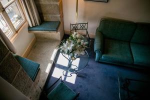 a living room with a green couch and a table with flowers at Palacio de los Velada in Avila