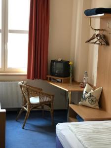 a room with a desk with a tv and a chair at Gästehaus & Café Leeze in Bad Dürkheim