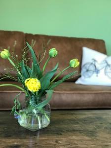 un vase en verre avec des fleurs jaunes sur une table dans l'établissement Gästehaus & Café Leeze, à Bad Dürkheim