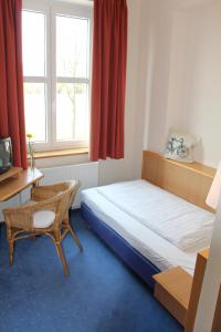 a bedroom with a bed and a desk and a window at Gästehaus & Café Leeze in Bad Dürkheim
