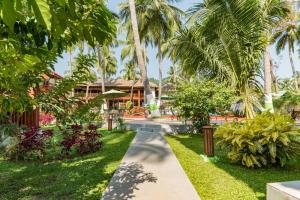 un chemin à travers les jardins d'un complexe avec des palmiers dans l'établissement Coral Reef Resort & Spa, Havelock, à Havelock Island