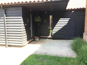 a black shed with a black door and a plant at The Stables Kings Ripton in Huntingdon