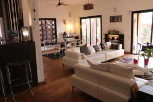 a living room with white couches and a dining room at Nyéléni maison sahel in Dakar