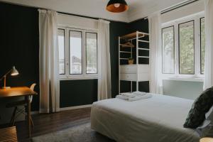 a bedroom with a bed and a desk and windows at Five Seven Nine Apartments in Porto