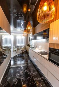 a kitchen with black marble floors and pendant lights at INN Royal House #1 in Brest