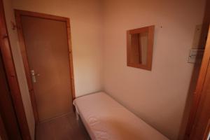 um pequeno quarto com uma cama e uma porta em Appt 4/5 pers. Les Saisies front de neige em Les Saisies